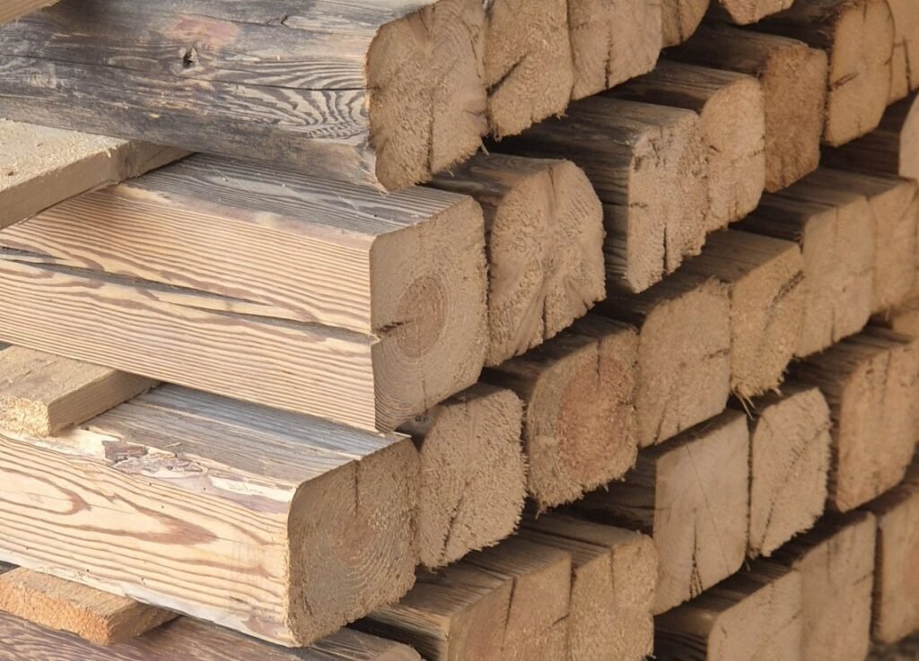 Altholzbalken aus Fichte sauber aufgestapelt – rustikale Struktur und helle Holzfarbe.